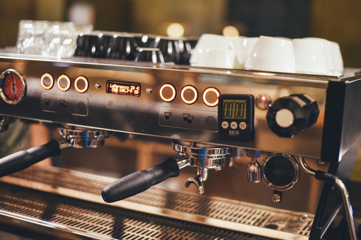 A warm-lit espresso machine with cups stacked on top, warming up before open